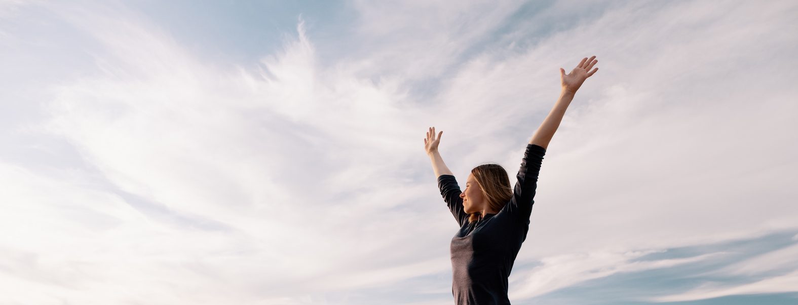 Woman enjoying a sense of freedom in an open field under a wide sky, reflecting the lightness many people seek through psychedelic integration support