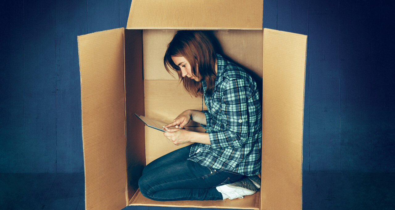 Girl sitting inside a box and using her phone