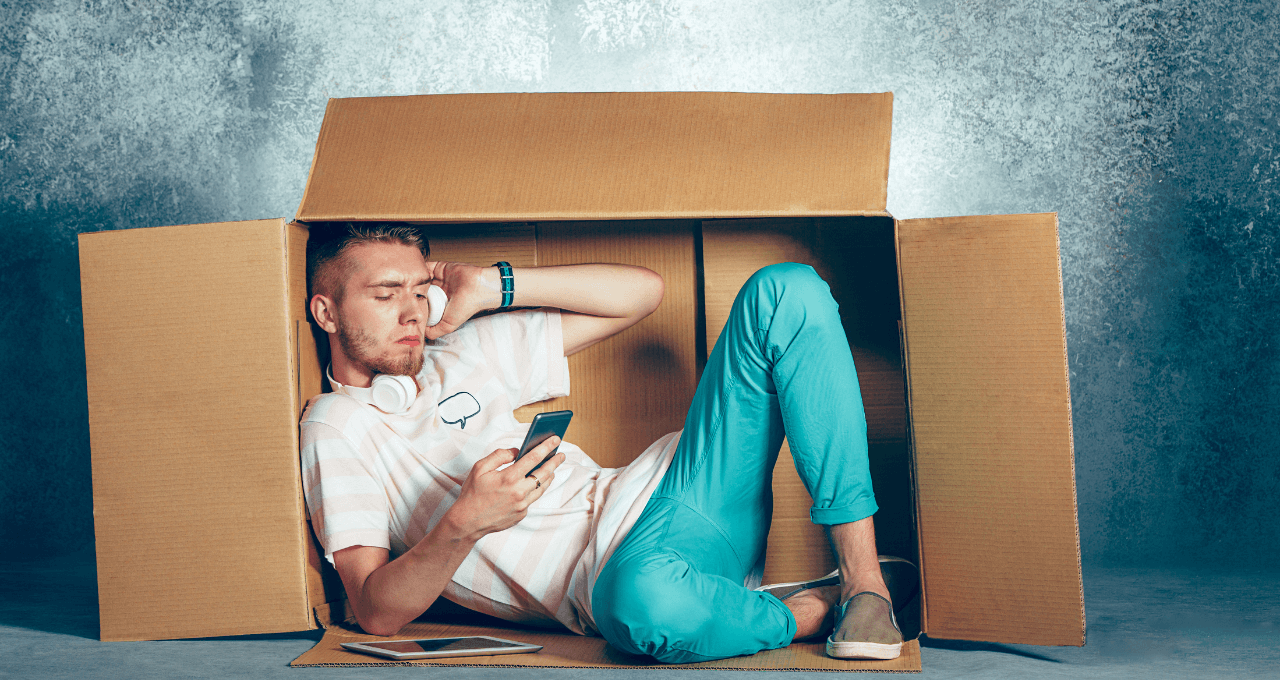 Man sitting inside a box with mobile on hand and listening a music